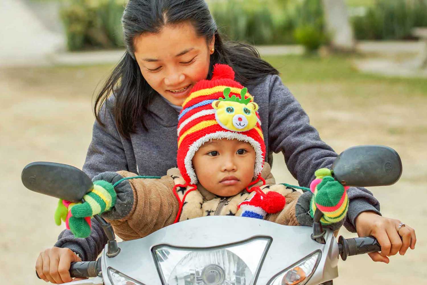 Laotische Mutter mit Kind auf Motorrad