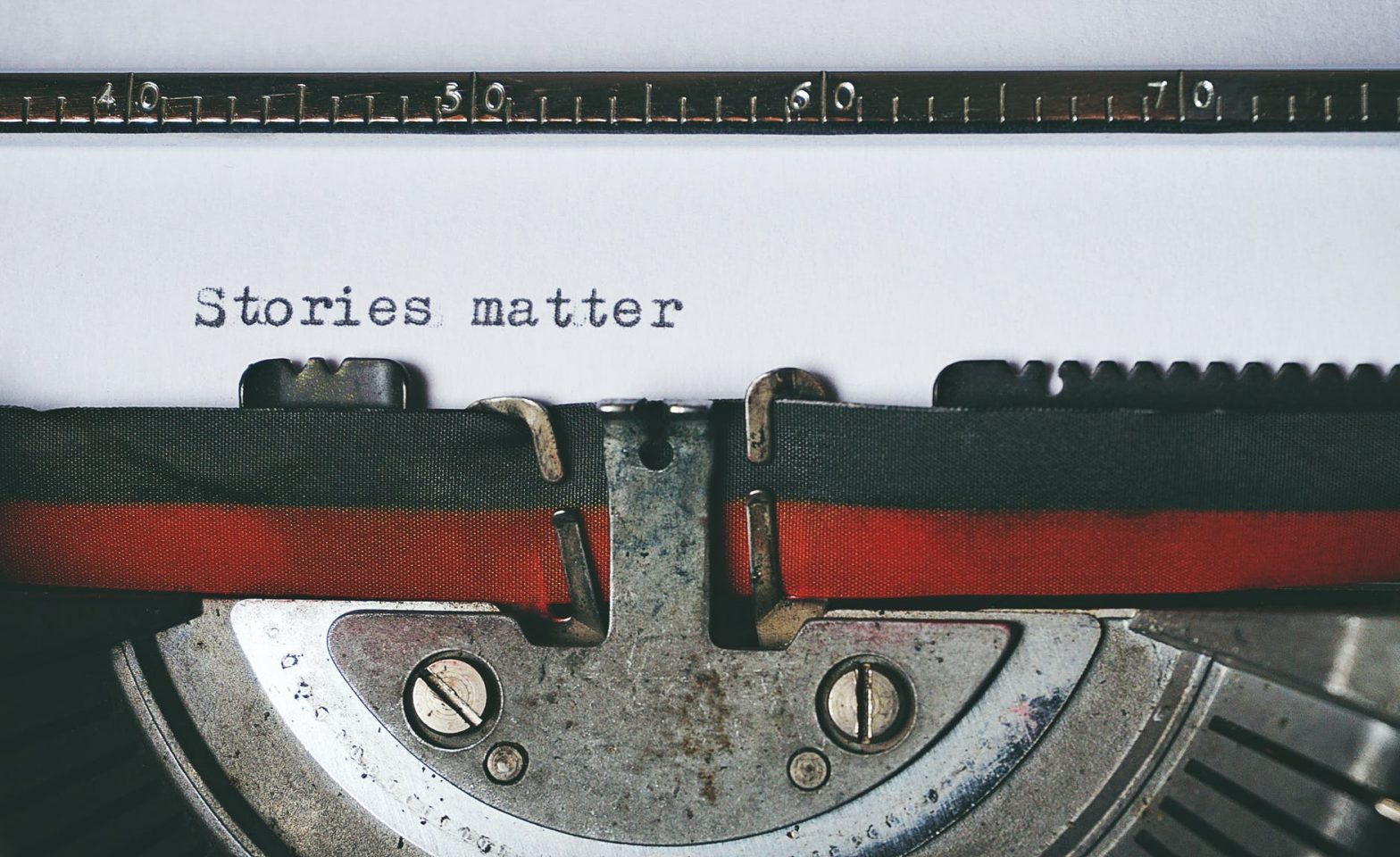 black and red typewriter, with "Stories matter" typed on the paper.