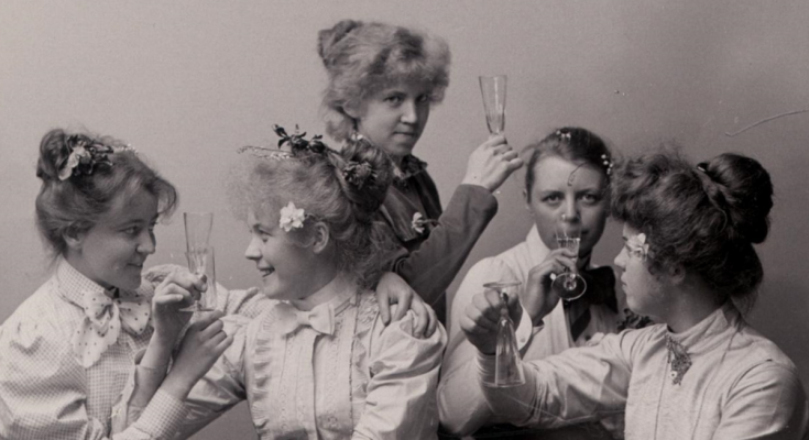 Fem kvinnor i festlig klädsel skålar med varandra.