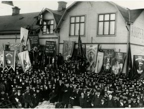 Ett svartvitt fotografi av en folkmassa av män med många fanor och banderoller.