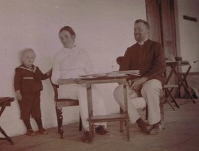 Ett svartvitt fotografi av en man en kvinna och ett barn vid ett bord.